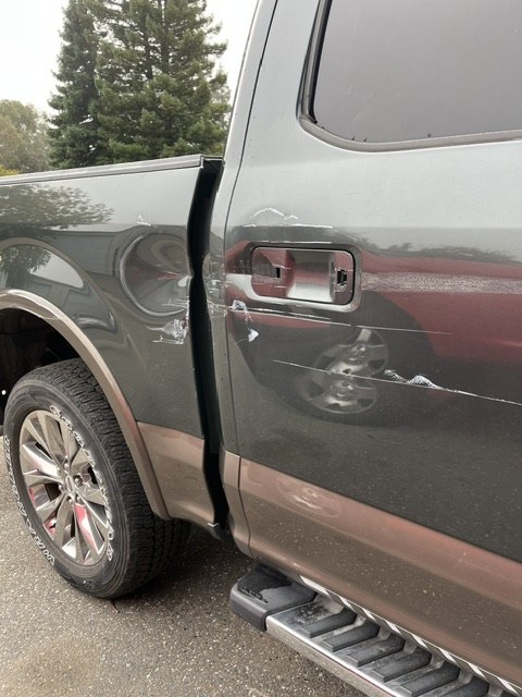 Dented aluminum door skin on an F-150 before repair