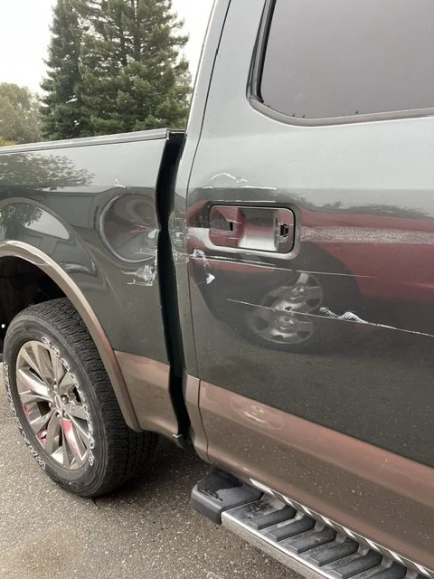 Dented aluminum door skin on an F-150 before repair
