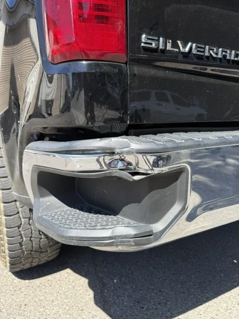 The Silverado's crushed rear bumper and damaged tailgate corner before repair